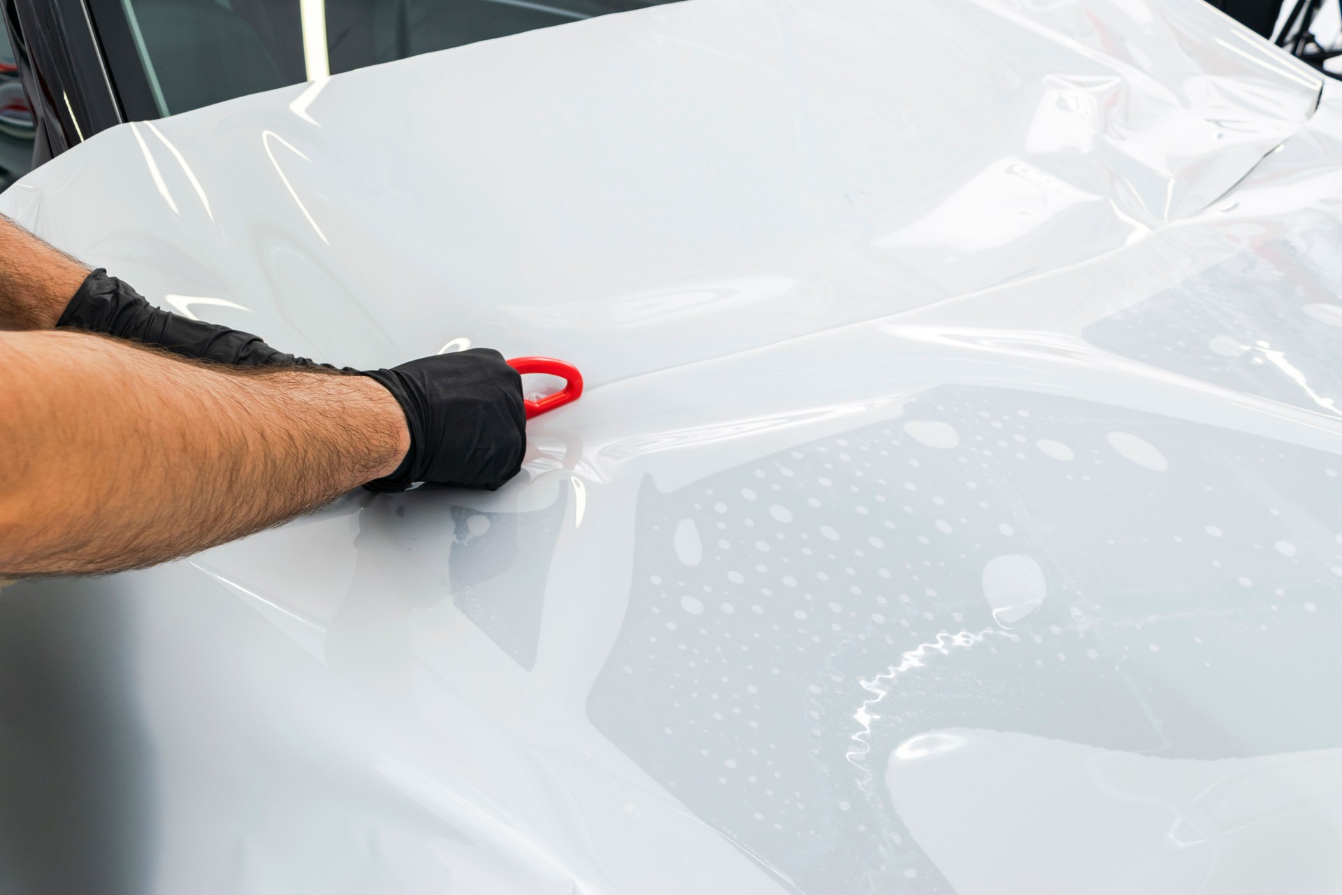 Auto Verpackung Spezialist Auto Vinylfolie oder Film aufsetzen. Schutzfolie auf dem Auto. Anwendung einen Schutzfilm auf das Auto mit Werkzeugen für die Arbeit. Auto Detaillierung. Transparente Folie. Auto-Lackschutz. Trimmen.